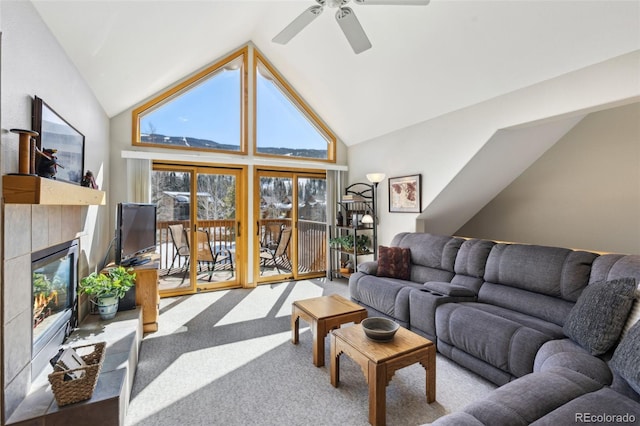 living room with a tiled fireplace, high vaulted ceiling, ceiling fan, and carpet floors