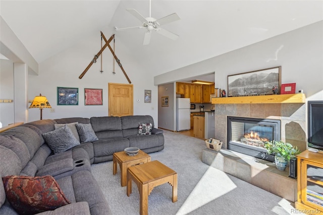 living area featuring light colored carpet, a fireplace, high vaulted ceiling, and a ceiling fan