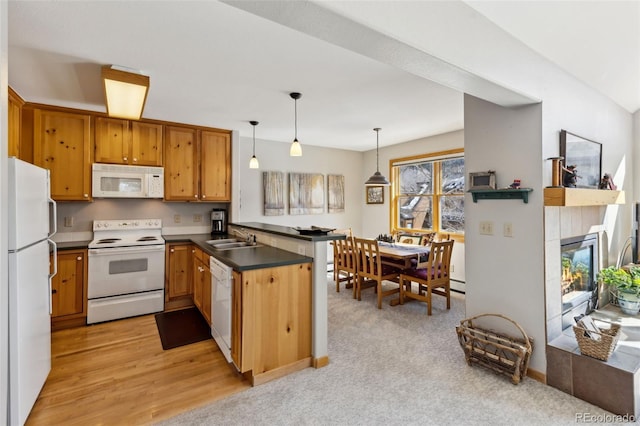 kitchen featuring white appliances, a peninsula, a sink, hanging light fixtures, and dark countertops