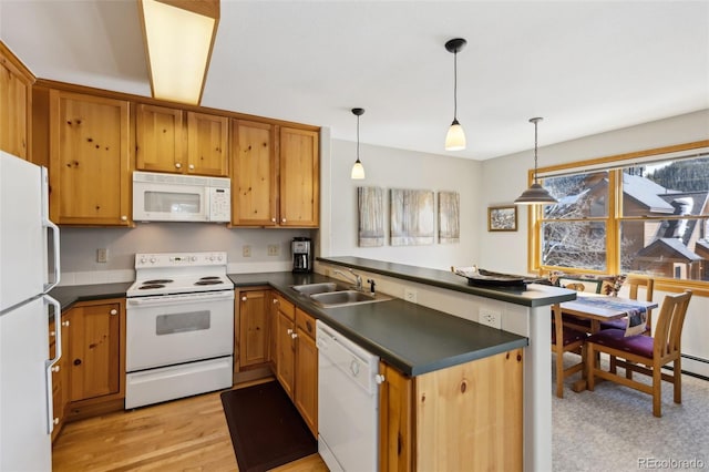 kitchen with dark countertops, a peninsula, hanging light fixtures, white appliances, and a sink