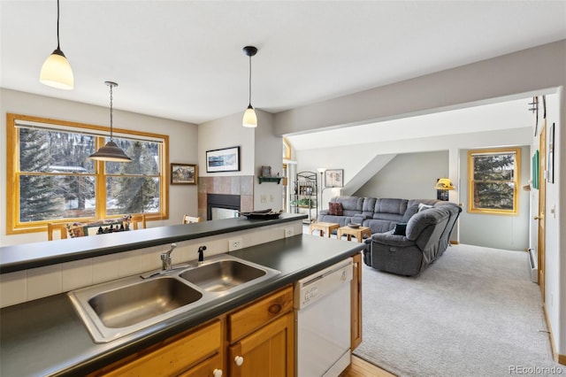 kitchen featuring dishwasher, dark countertops, decorative light fixtures, and a sink