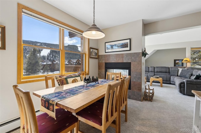 dining area featuring baseboard heating, carpet flooring, and a tiled fireplace