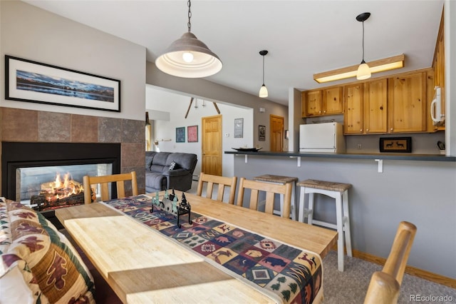 carpeted dining space with baseboards and a tile fireplace