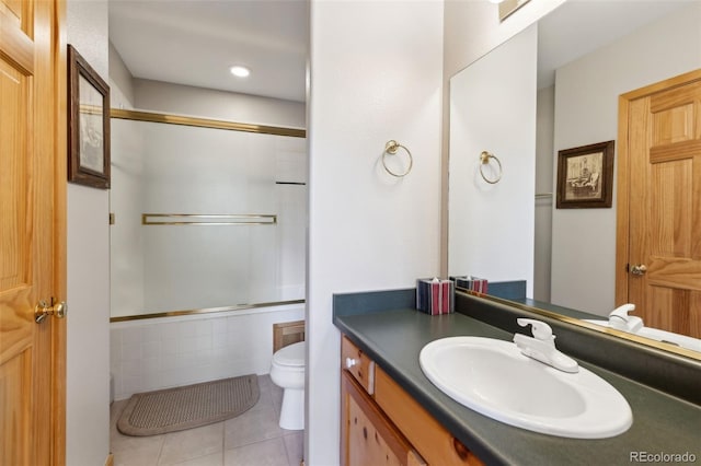 bathroom featuring combined bath / shower with glass door, toilet, vanity, and tile patterned flooring