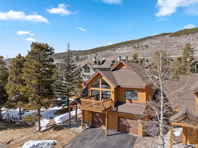 exterior space with aphalt driveway, a balcony, roof with shingles, and an attached garage