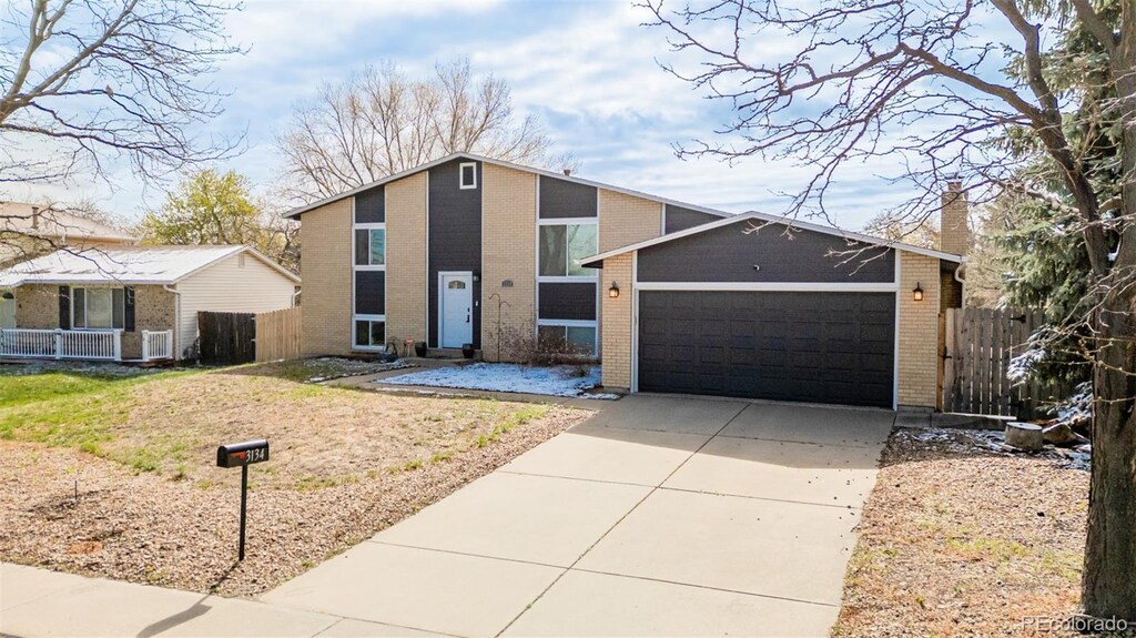 3134 S Fairplay St, Aurora, CO 80014 - mid-century home featuring concrete driveway, a chimney, an attached garage, fence, and brick siding