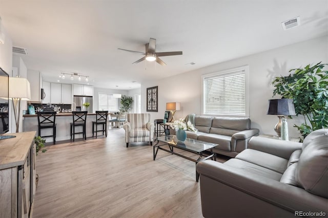 living area with visible vents, light wood-type flooring, and a ceiling fan
