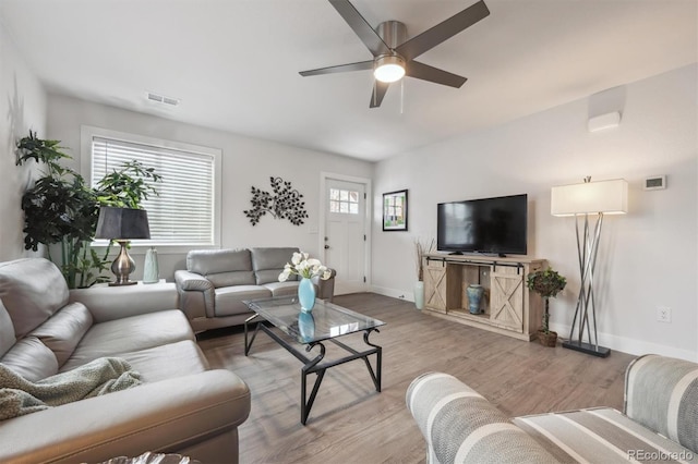 living room with baseboards, ceiling fan, visible vents, and light wood-style floors