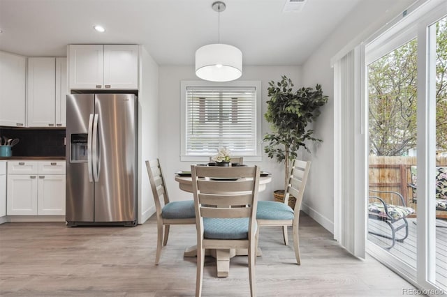 dining room featuring baseboards, a healthy amount of sunlight, and light wood-style floors