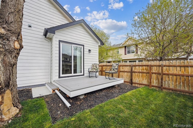 back of property with a yard, a deck, and fence