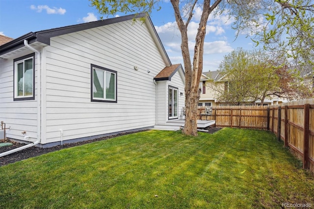 back of property with a fenced backyard and a lawn