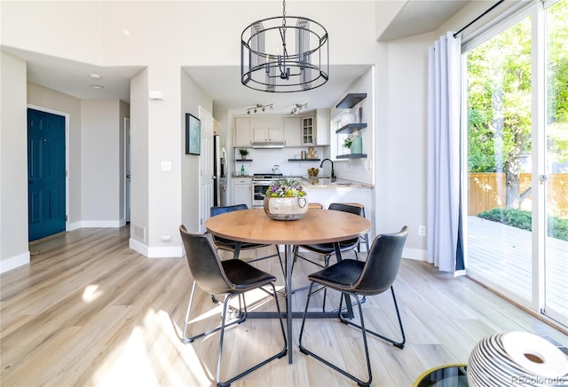 dining room featuring sink, an inviting chandelier, and light hardwood / wood-style flooring