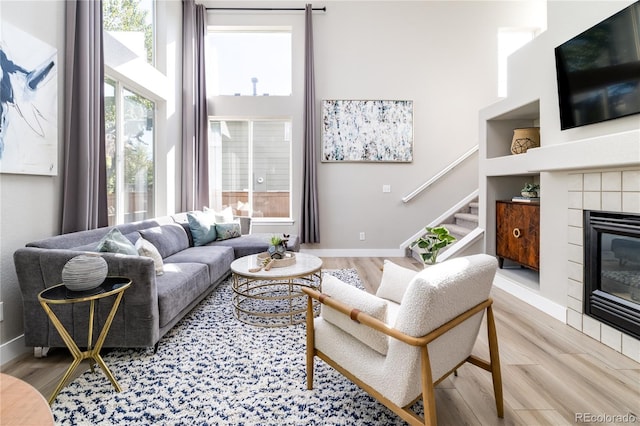 living room featuring a tile fireplace, plenty of natural light, built in shelves, and hardwood / wood-style floors