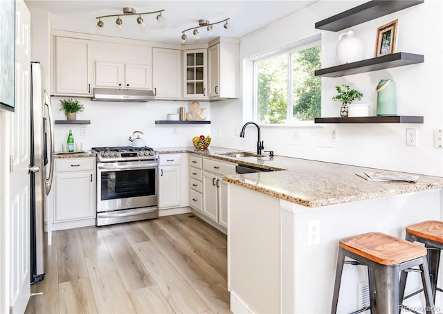 kitchen featuring sink, kitchen peninsula, white cabinetry, stainless steel appliances, and a kitchen bar