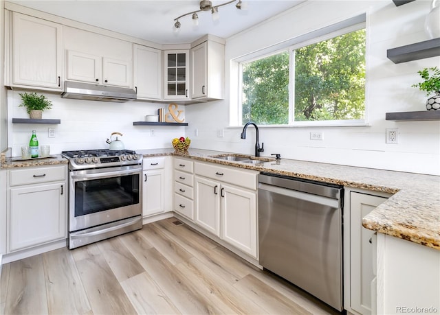 kitchen with white cabinets, appliances with stainless steel finishes, sink, and light stone counters