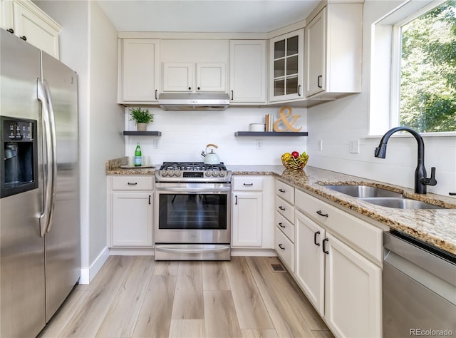 kitchen featuring light stone counters, sink, white cabinetry, appliances with stainless steel finishes, and light wood-type flooring