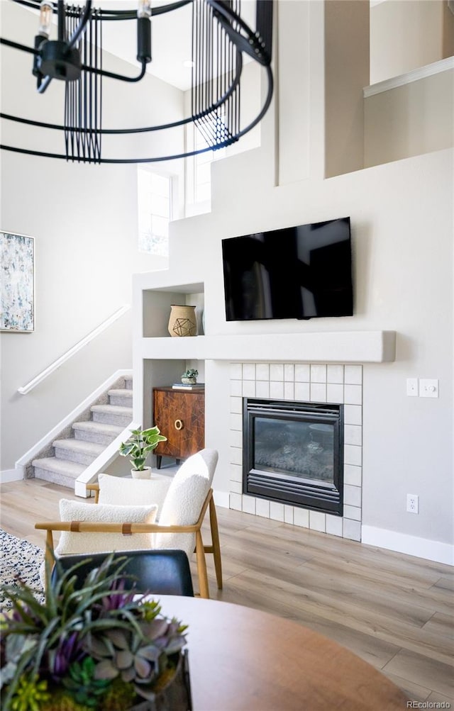 living room featuring hardwood / wood-style flooring, a fireplace, a towering ceiling, and a chandelier