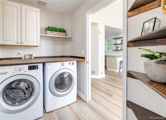 laundry room with cabinets, light hardwood / wood-style flooring, and washer and dryer