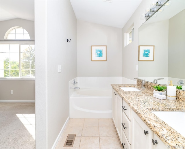 bathroom featuring lofted ceiling, a tub, tile patterned flooring, and vanity