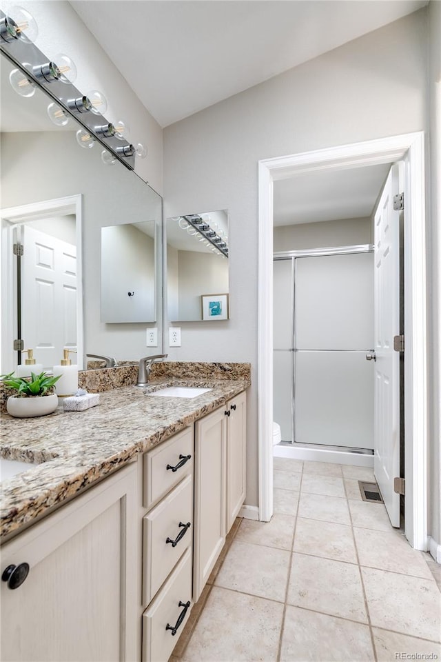 bathroom with a shower with door, tile patterned floors, vanity, and toilet