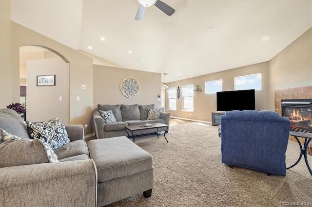 56330 E 37th Ct, Strasburg, CO 80136 - living room with carpet, ceiling fan, arched walkways, a tiled fireplace, and baseboards