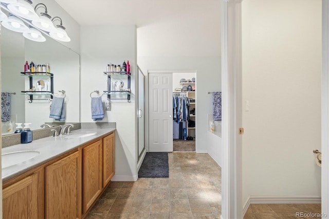 56330 E 37th Ct, Strasburg, CO 80136 - bathroom with a spacious closet, baseboards, a sink, and double vanity