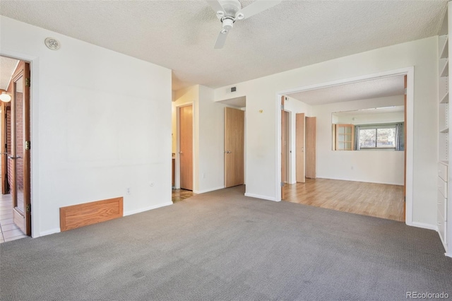 carpeted empty room featuring baseboards, a ceiling fan, visible vents, and a textured ceiling