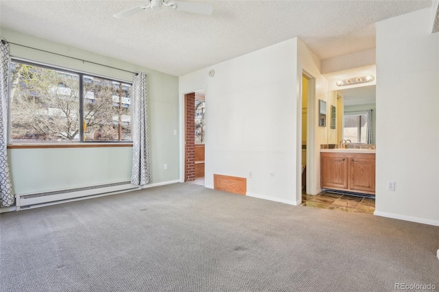 unfurnished bedroom with carpet floors, ensuite bath, baseboards, a textured ceiling, and baseboard heating