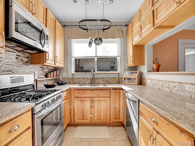 kitchen with appliances with stainless steel finishes, light brown cabinetry, tasteful backsplash, sink, and light stone countertops