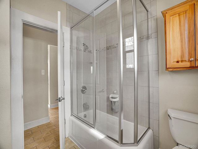 bathroom featuring hardwood / wood-style floors, shower / bath combination with glass door, and toilet