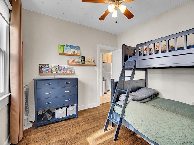 bedroom with ceiling fan, hardwood / wood-style floors, and stainless steel refrigerator