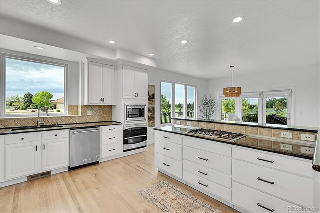 kitchen with appliances with stainless steel finishes, a sink, recessed lighting, backsplash, and light wood-style floors