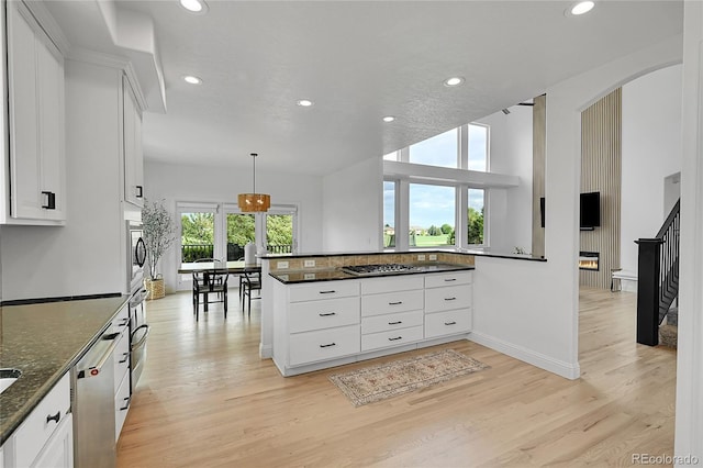 kitchen with recessed lighting, light wood-style floors, stainless steel appliances, white cabinetry, and dark stone counters