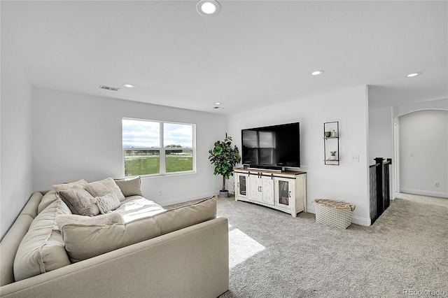 living area with arched walkways, light colored carpet, recessed lighting, and baseboards