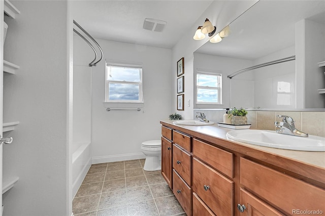 full bath featuring double vanity, toilet, and baseboards