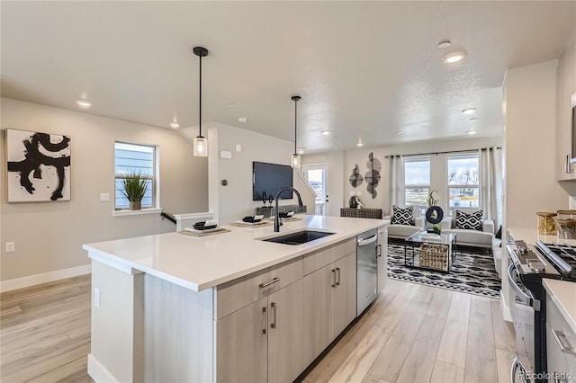 kitchen featuring sink, a center island with sink, light wood-type flooring, and stainless steel appliances