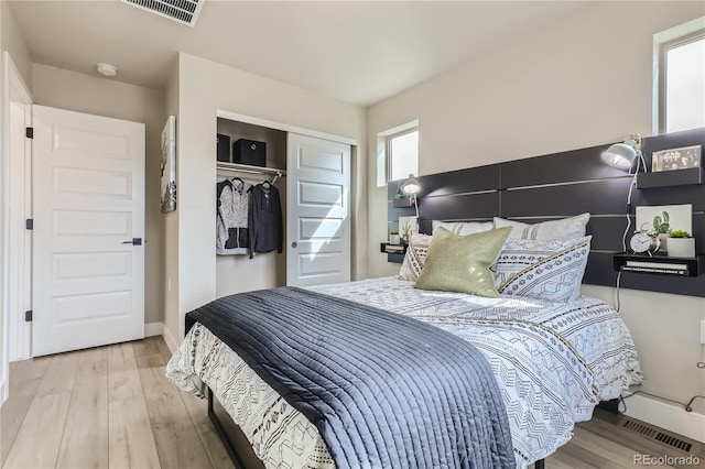 bedroom featuring light hardwood / wood-style floors, multiple windows, and a closet