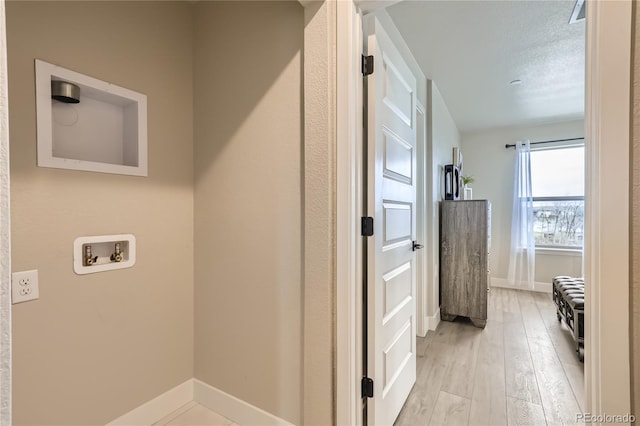 hallway with a textured ceiling and light wood-type flooring