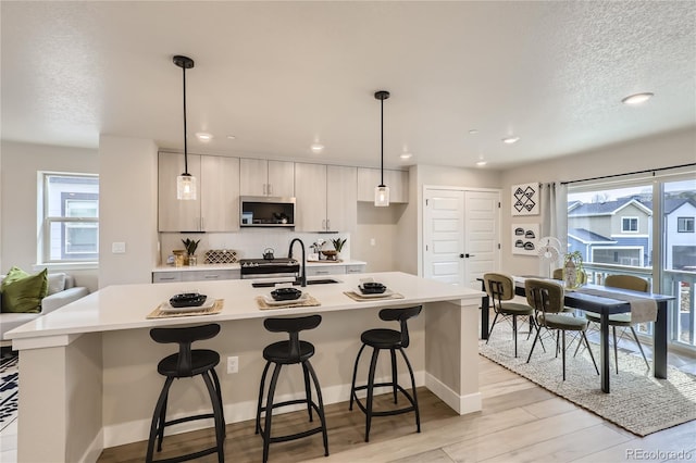 kitchen featuring a wealth of natural light, pendant lighting, and a center island with sink