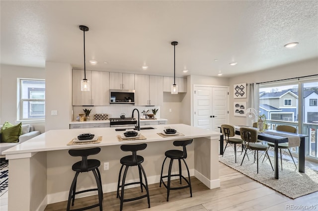 128 E Douglas St, Superior, CO 80027 - kitchen with a sink, stainless steel microwave, light countertops, an island with sink, and healthy amount of natural light