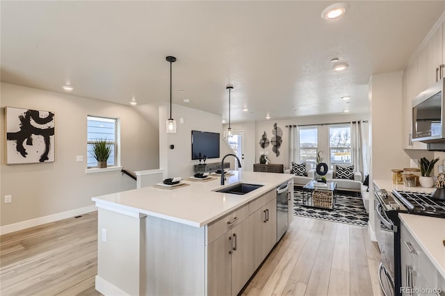 kitchen featuring appliances with stainless steel finishes, sink, light hardwood / wood-style floors, and an island with sink