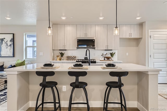 kitchen with decorative light fixtures, a kitchen breakfast bar, and a kitchen island with sink