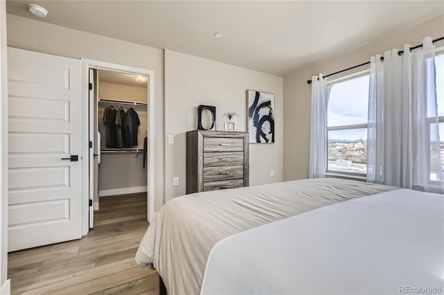 bedroom with a closet, light hardwood / wood-style flooring, and a walk in closet