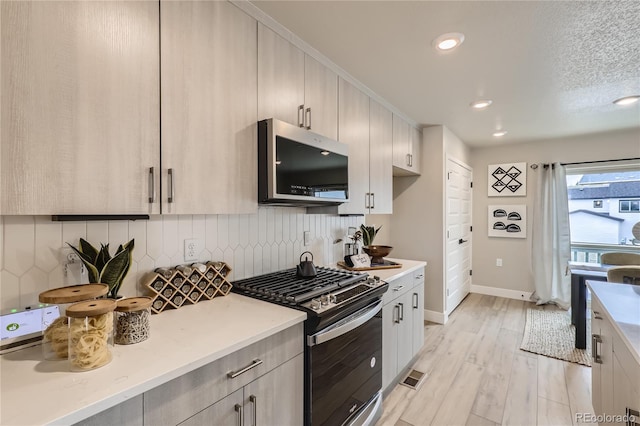 kitchen featuring appliances with stainless steel finishes, a textured ceiling, light wood-type flooring, and decorative backsplash