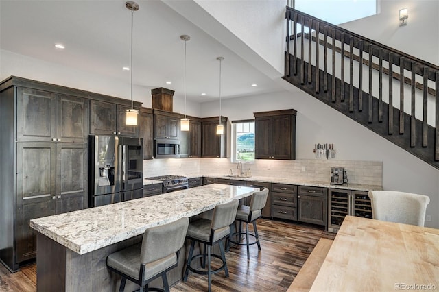 701 Saddle Ridge Cir, Granby, CO 80446 - kitchen featuring stainless steel appliances, beverage cooler, dark brown cabinets, dark wood-style floors, and decorative backsplash