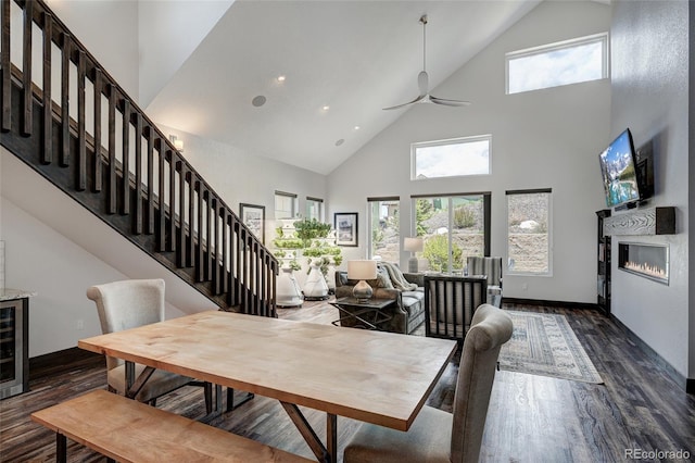 701 Saddle Ridge Cir, Granby, CO 80446 - dining area featuring high vaulted ceiling, dark wood-style flooring, stairs, a ceiling fan, and a glass covered fireplace
