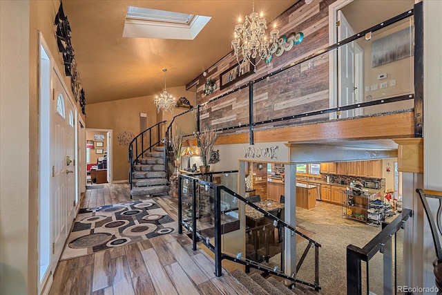 interior space with a skylight, an inviting chandelier, high vaulted ceiling, and hardwood / wood-style floors