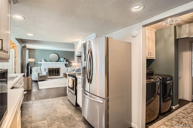 6494 W 85th Ave, Arvada, CO 80003 - kitchen featuring stainless steel appliances, washing machine and clothes dryer, a textured ceiling, light countertops, and open floor plan