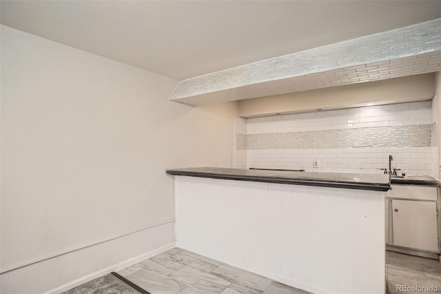 6494 W 85th Ave, Arvada, CO 80003 - kitchen with tasteful backsplash, dark countertops, white cabinetry, and a peninsula
