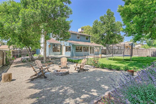6494 W 85th Ave, Arvada, CO 80003 - rear view of house with an outdoor fire pit, a trampoline, a fenced backyard, and a patio